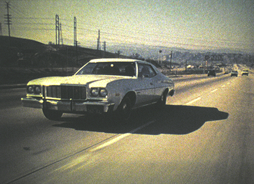 Film still from Desert People: image shows a 1970s American car moving down a highway