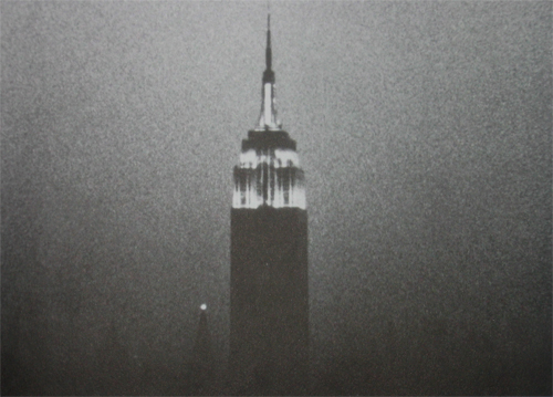 Film still from Empire by Andy Warhol. Image shows a black and white image of the Empire State Building at night
